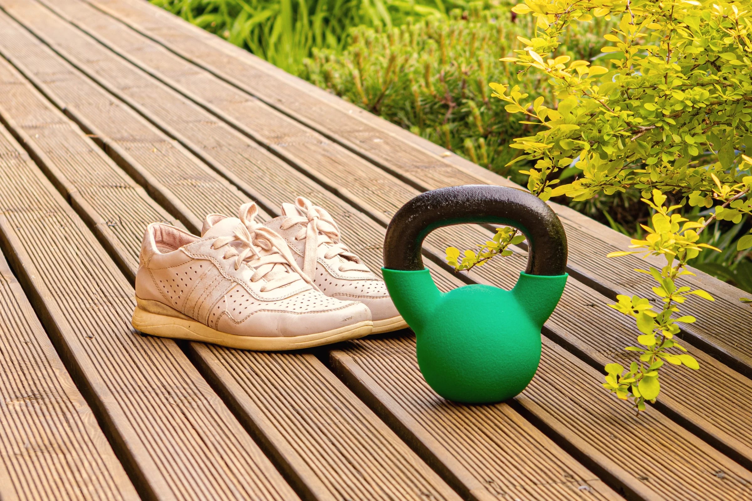 Trainers and a green kettlebell on a garden deck
