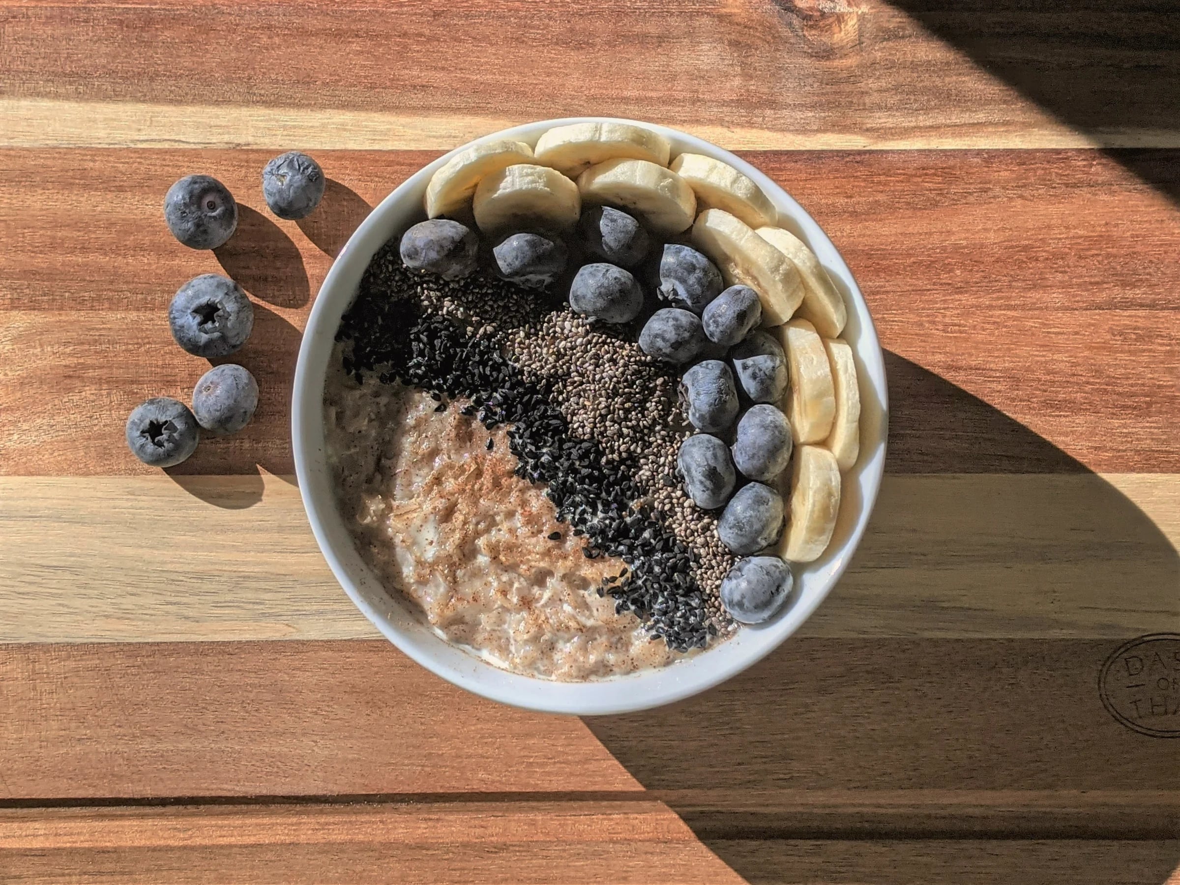 A bowl of porridge topped with blueberries, banana and seeds